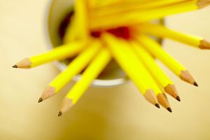 metal cup on yellow table filled with sharpened yellow pencils