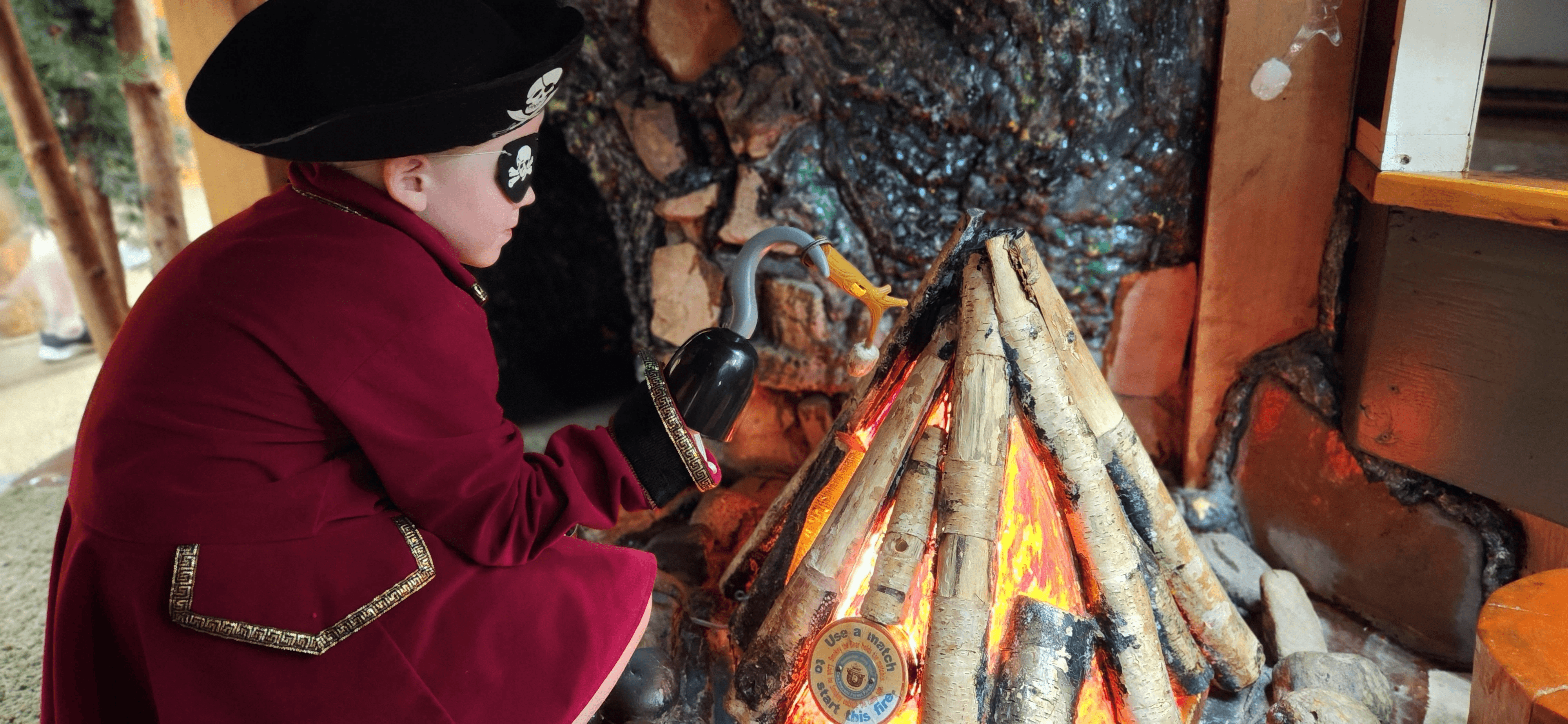 A child in a pirate costume playing at a toy campfire.