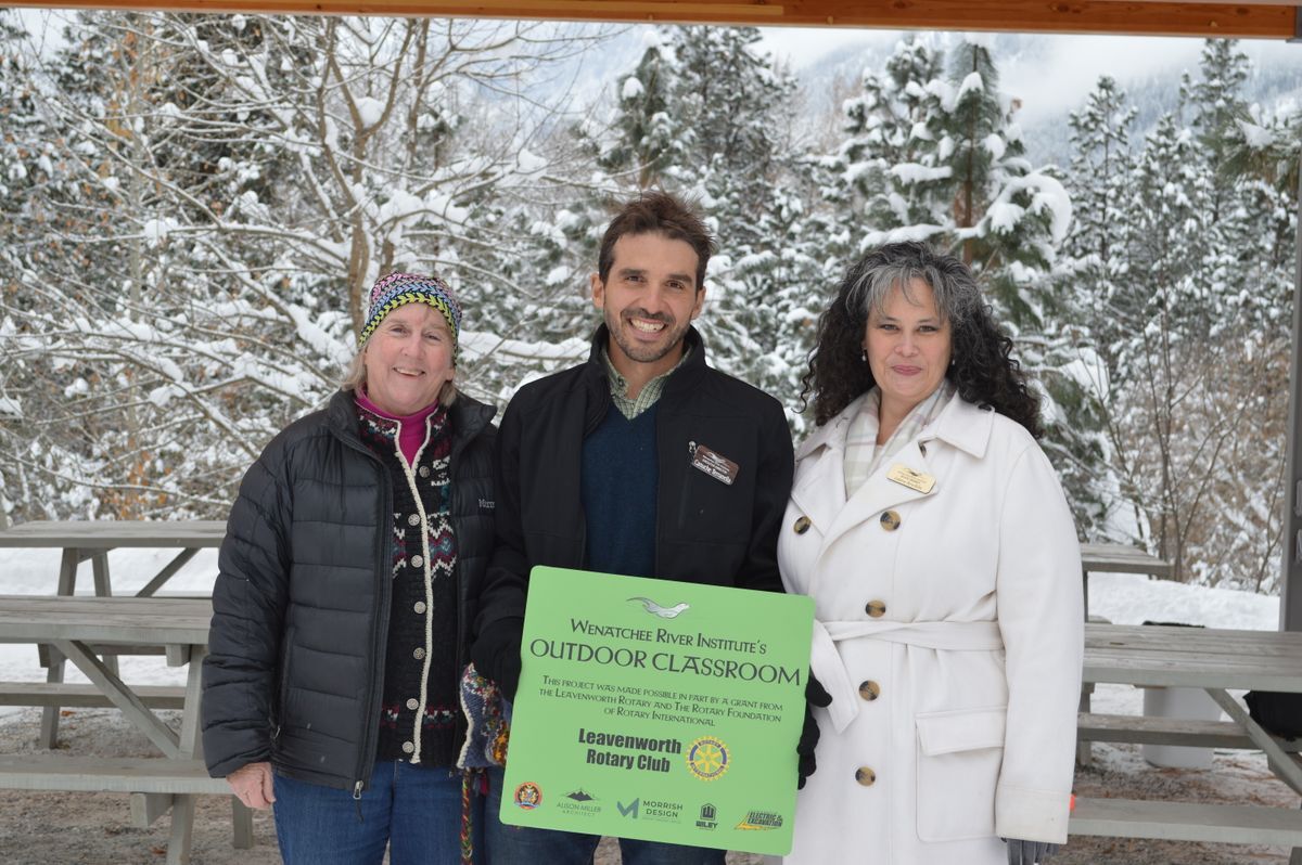 Three people holding the Outdoor Classroom sign at the Ribbon Cutting in December 2022.