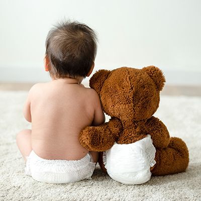 Baby and teddy bear both wearing diapers