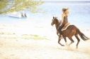 This is a picture a girl riding a horse on the beach