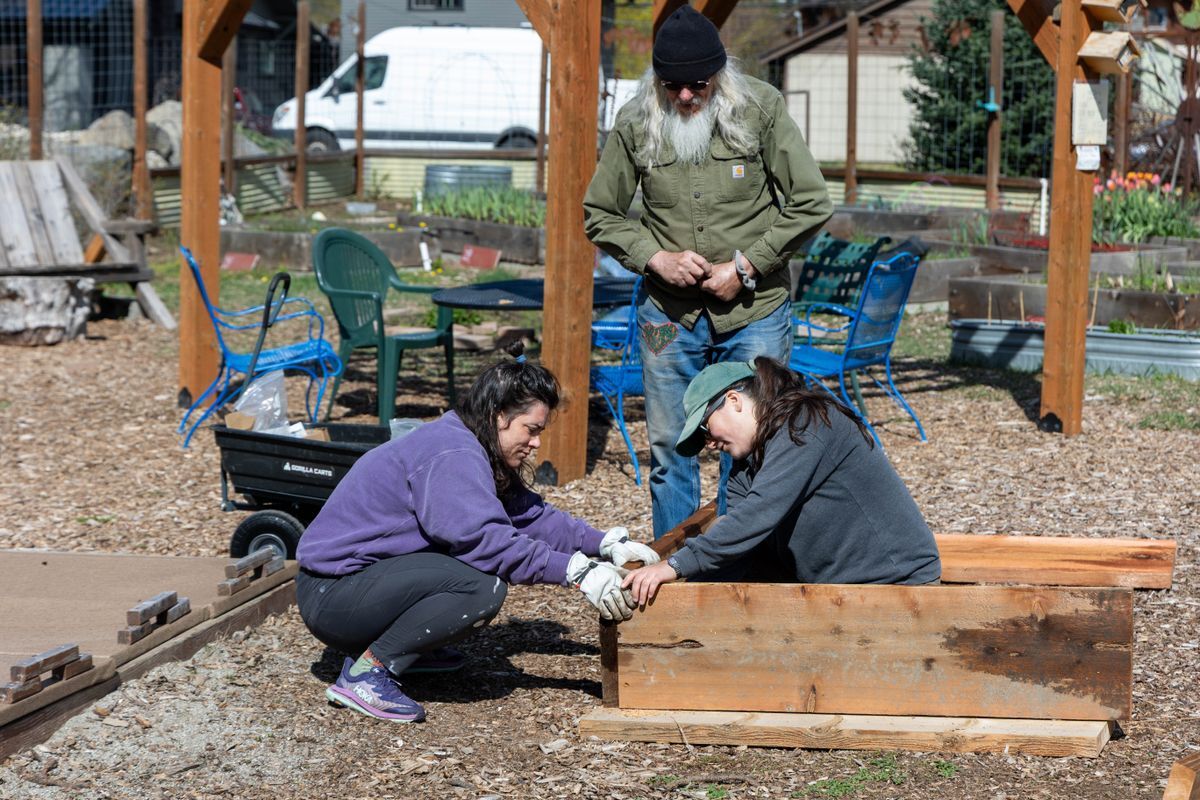 Three volunteers working together to rebuild a planter box at the Community Garden.