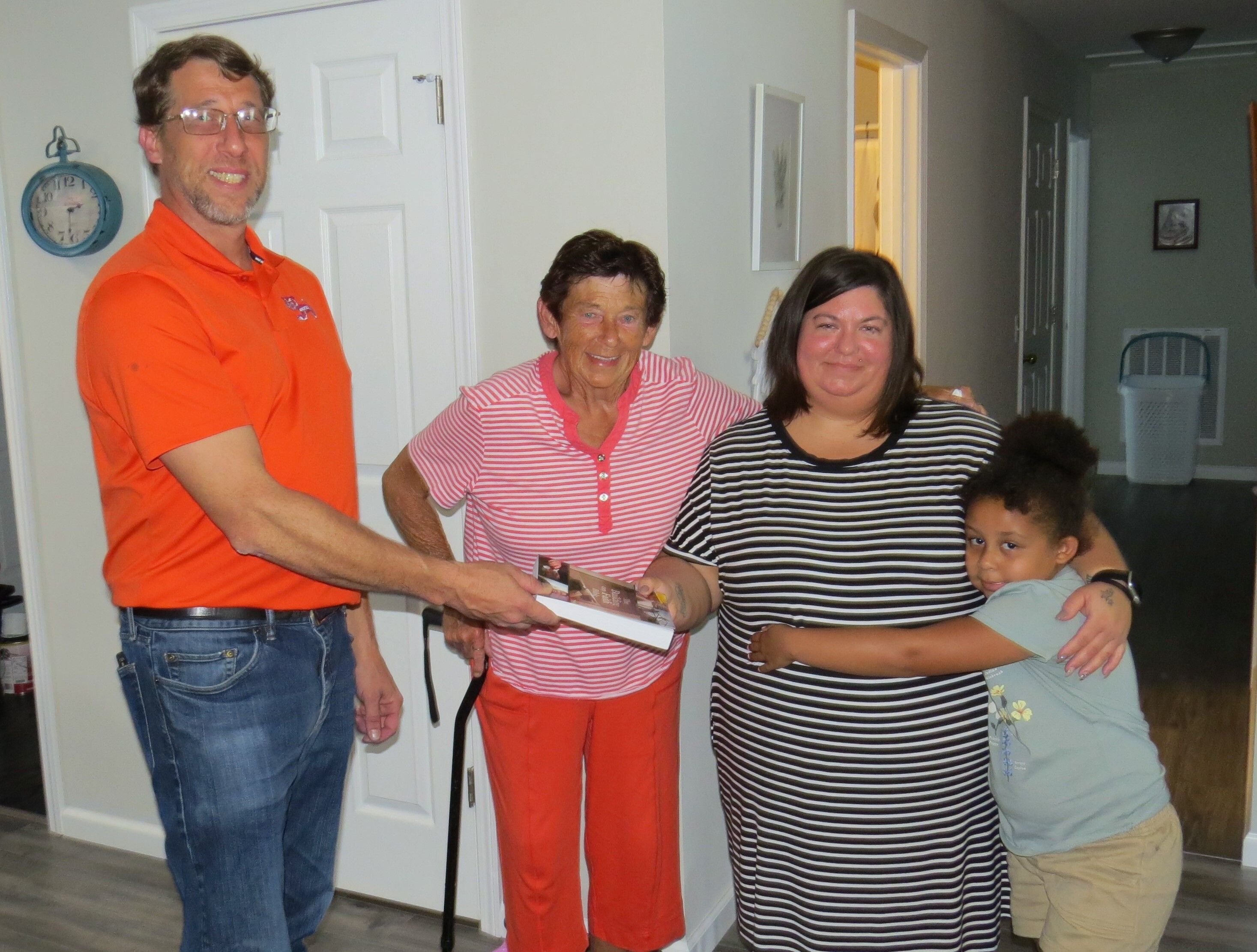 Alley Linder, president of PCHFH Board of Directors, presents a Bible to the Roper family