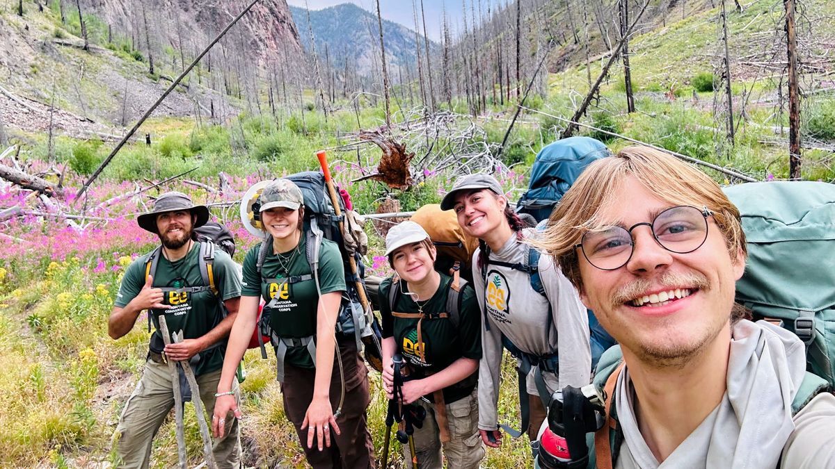 [Image Description: An MCC crew wears backpacks and poses in the backcountry while holding tools.]