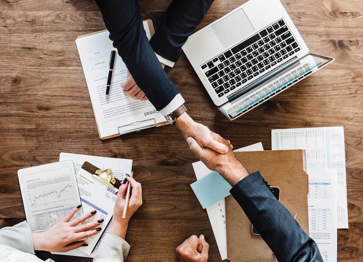 People shaking hands making a possible business decision over paperwork.