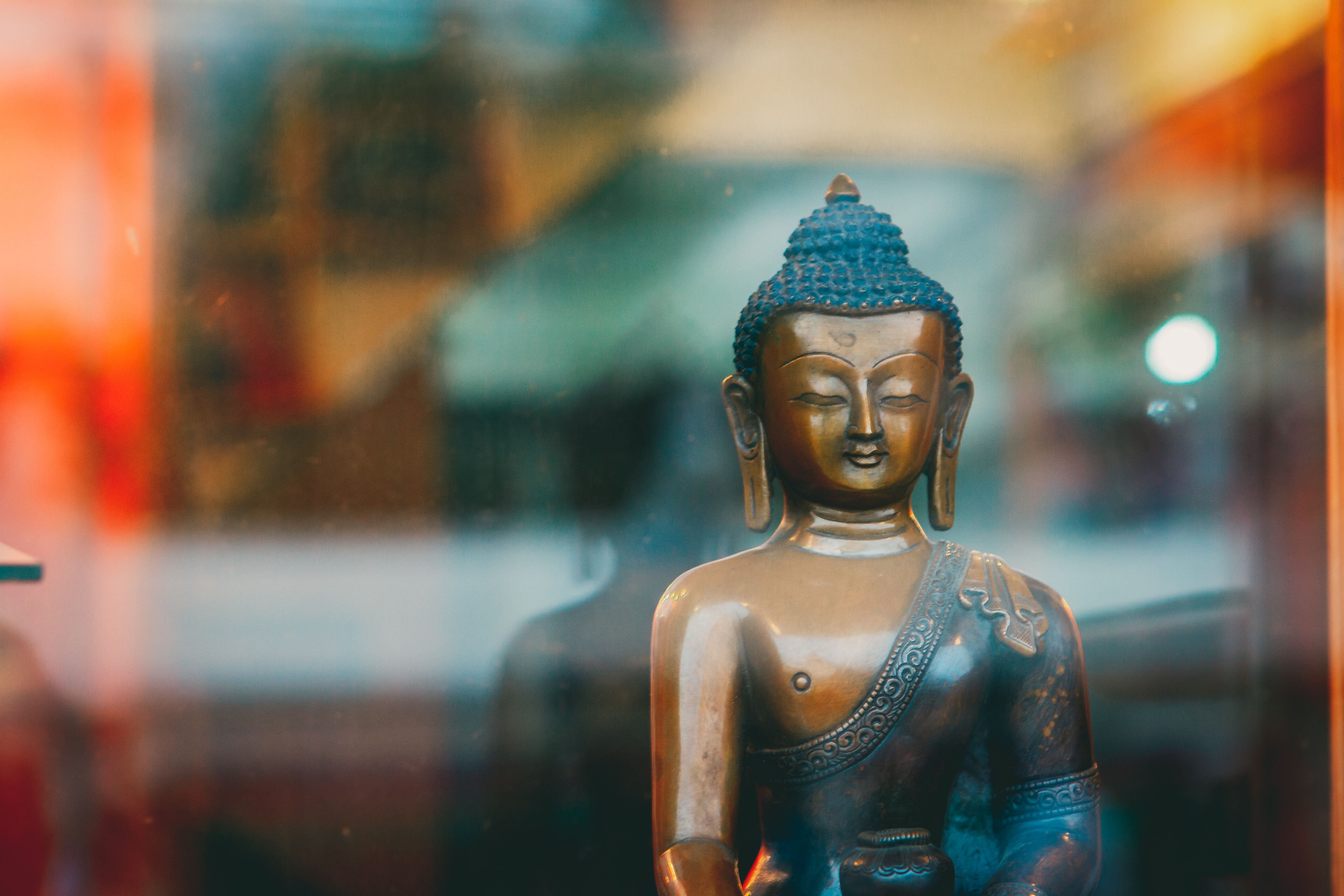 Image of Buddha statue in the window with glare on the glass.