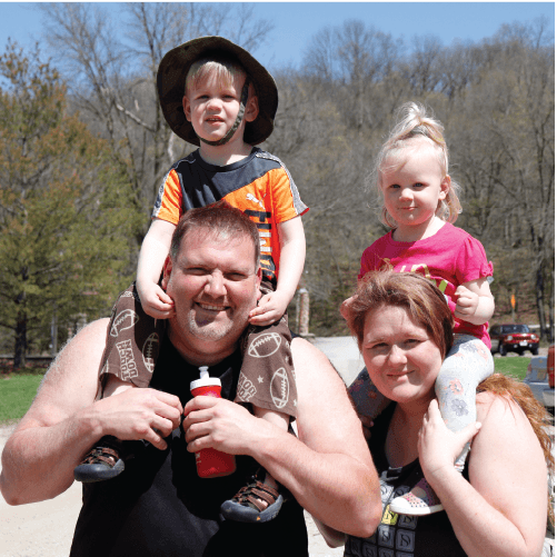 A mother and father holding their children on their shoulders at Spring Family Camp 2022. 