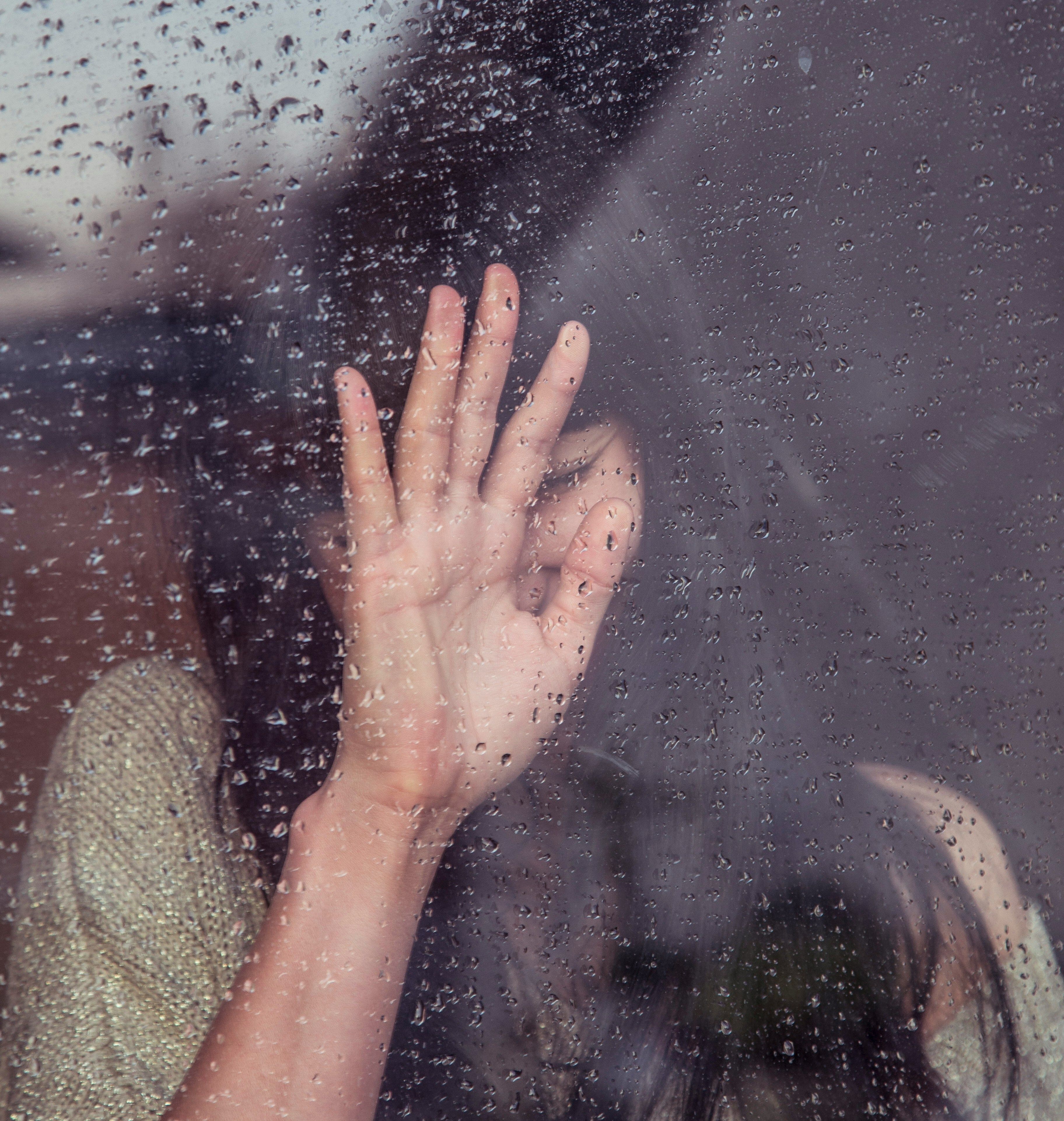 Woman inside a window with rain droplets on it