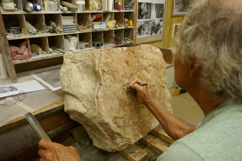 Dale beginning to draw the outline of the Red Wolf in the stone