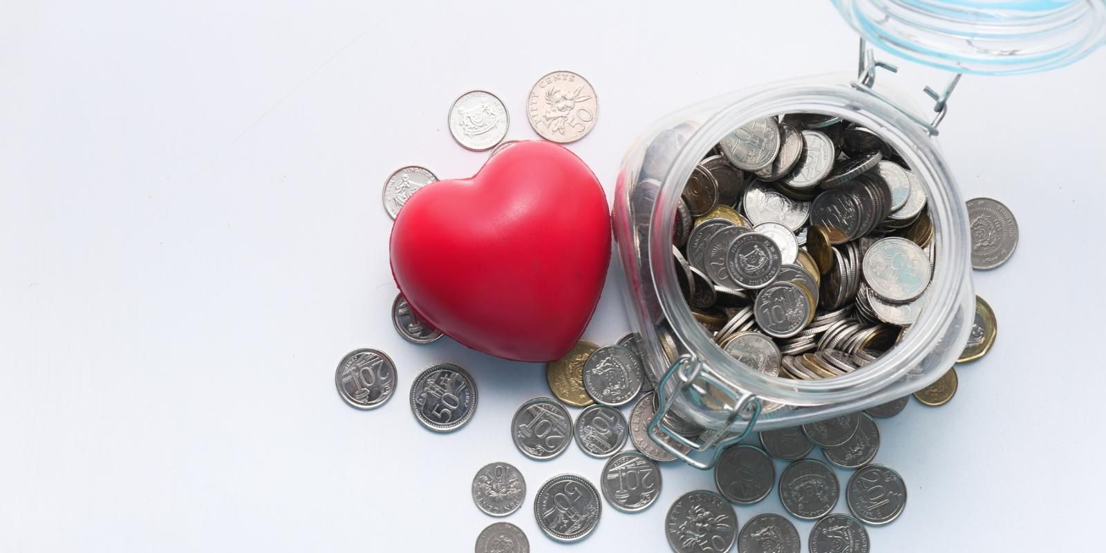 Jar of coins next to a red heart.