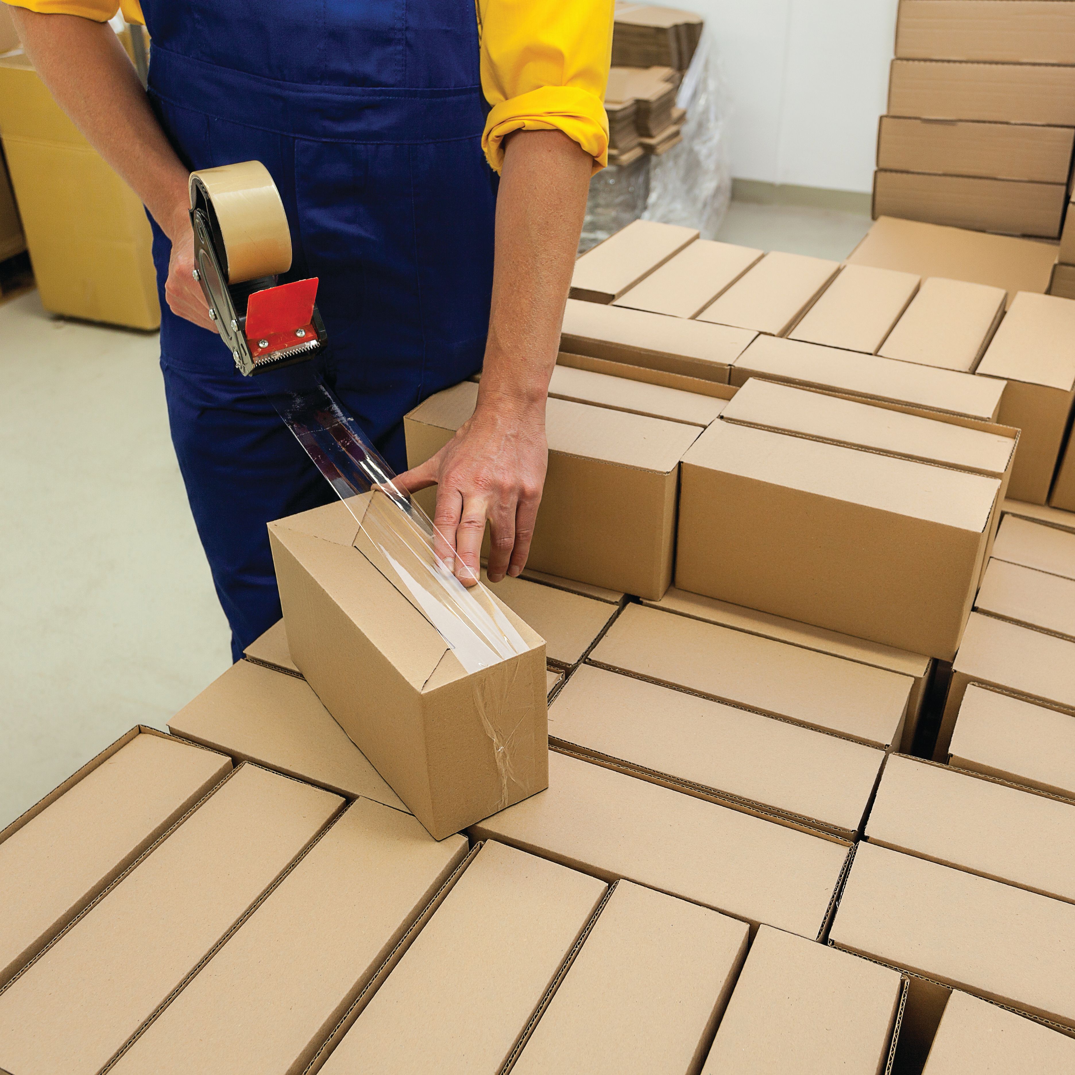 worker closing shipping box with packaging tape