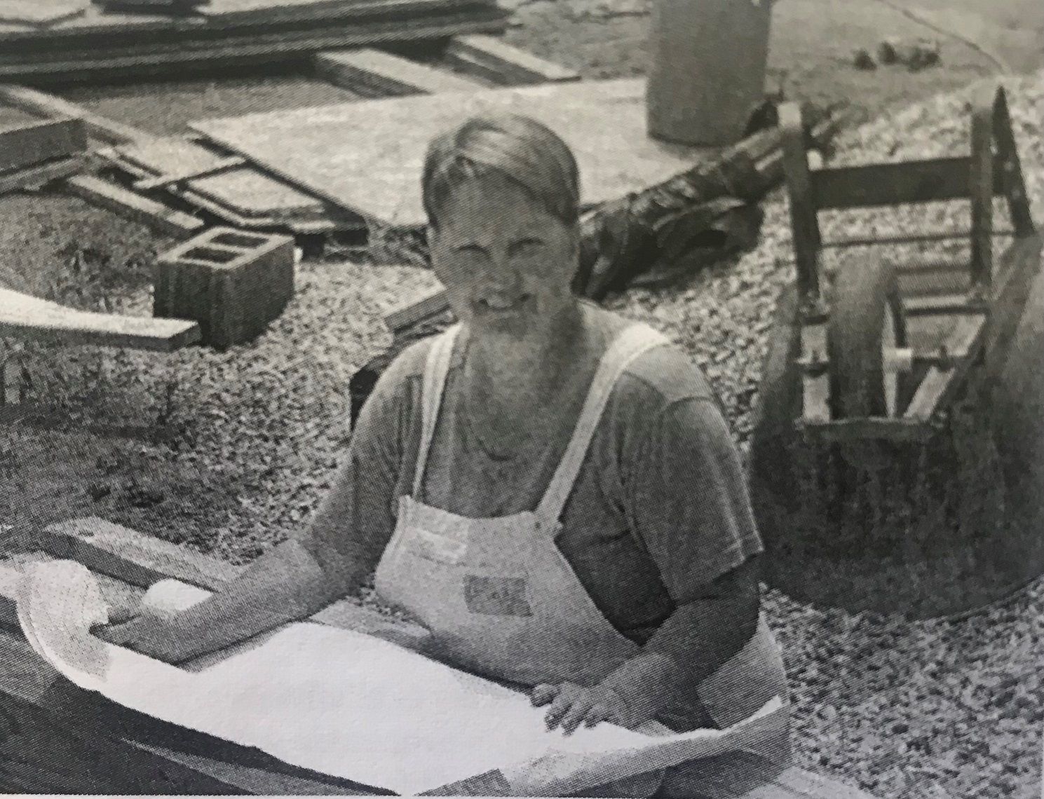 Black and white photo of Cindy Sanders smiling looking over a blueprint. 