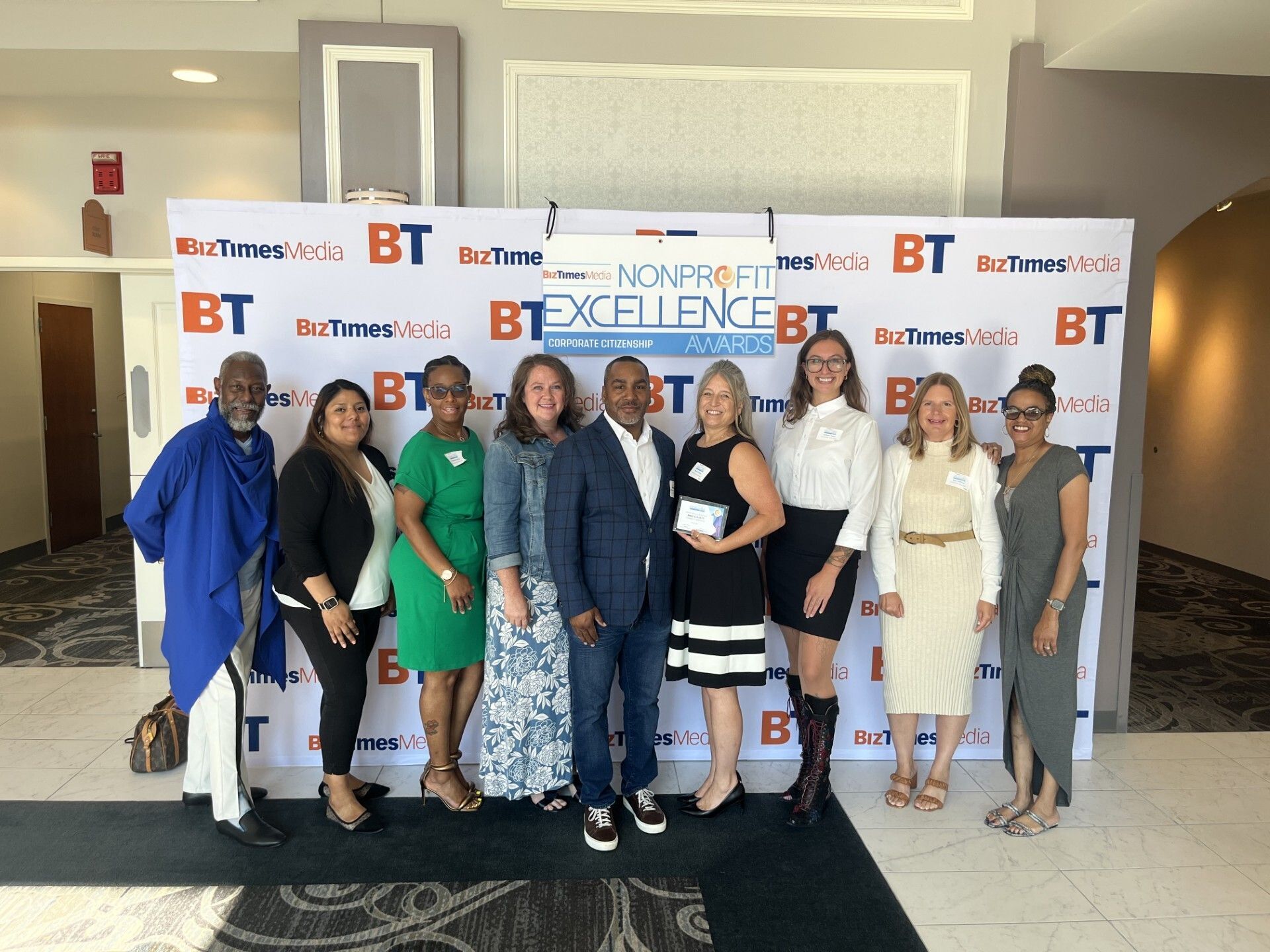 The Community Advocates team poses for a picture in front of BizTimes Media's Nonprofit Excellence Awards banner. Amongst them is Andi Elliott, finalist for the the Nonprofit Executive of the Year award. 
