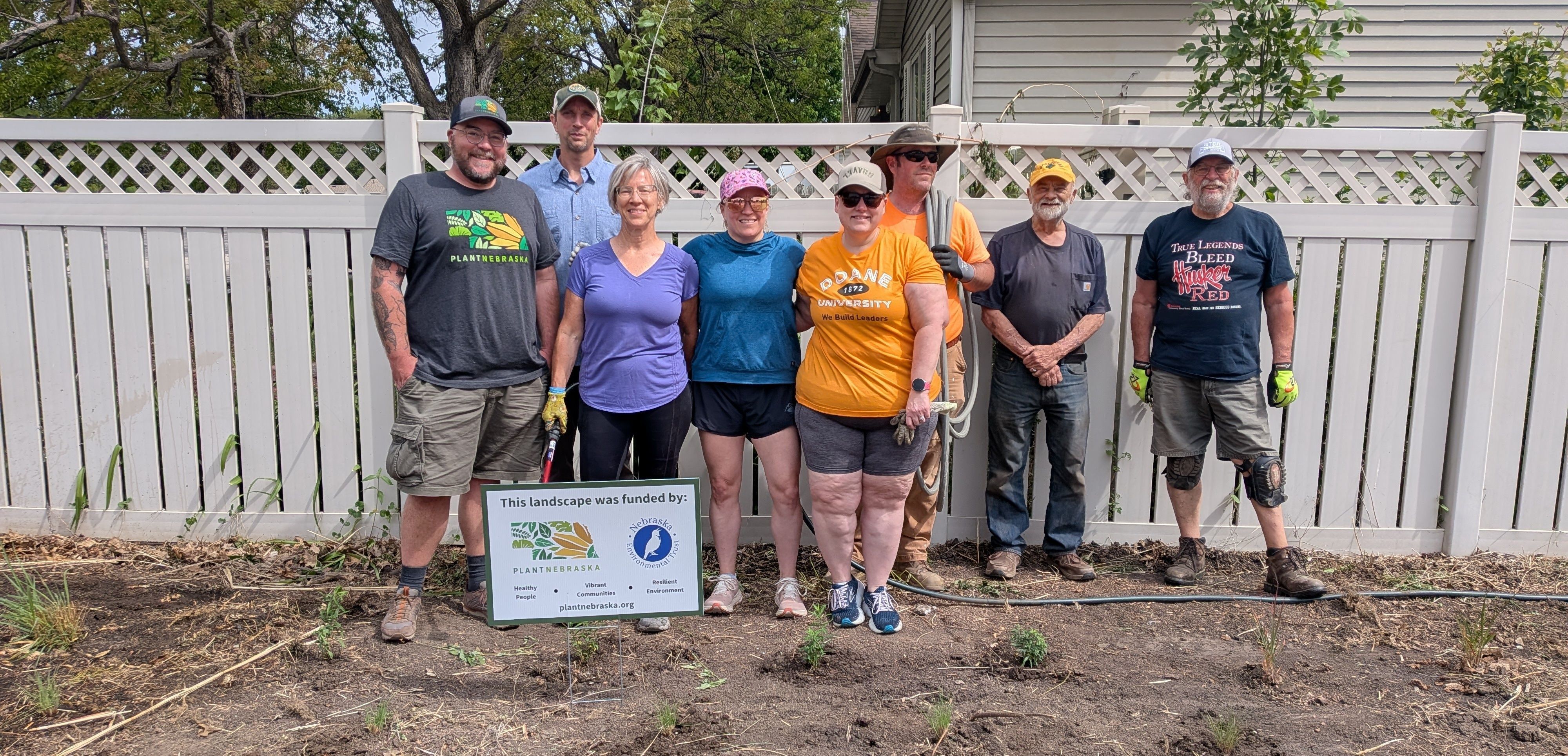 A group of people holding gardening tools plant a garden 