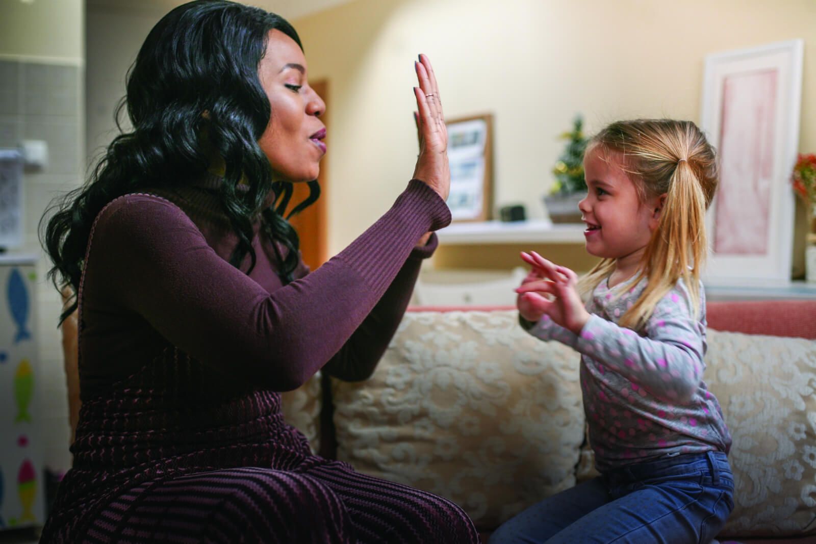 A CASA volunteer plays paddy cake with a young girl living in foster care.