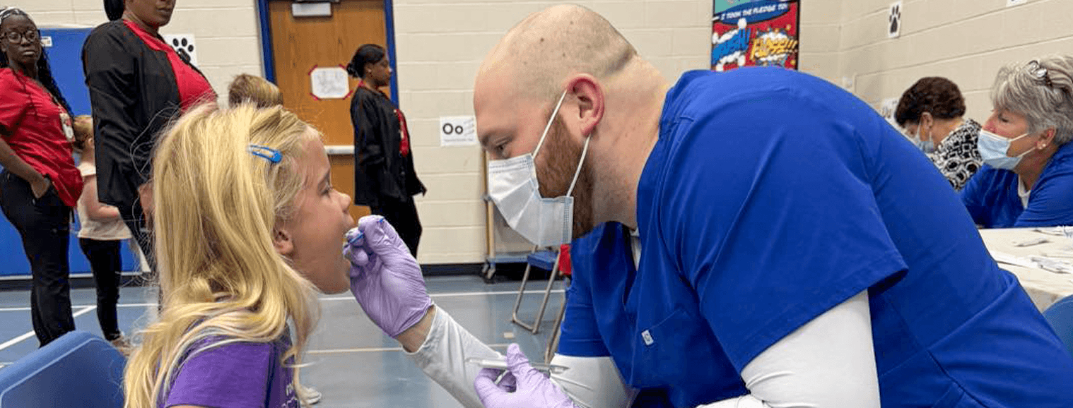 man providing dental screening to young girl