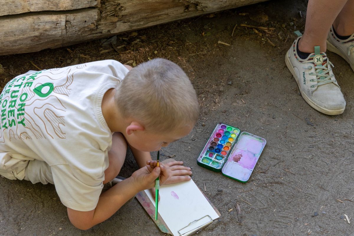 Young child painting with water colors on the ground during a WRI Paint and Stroll event in 2025.