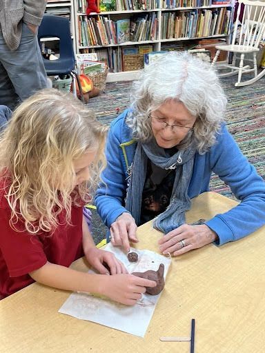 Volunteer helping a student sculpt an American Red Wolf out of clay