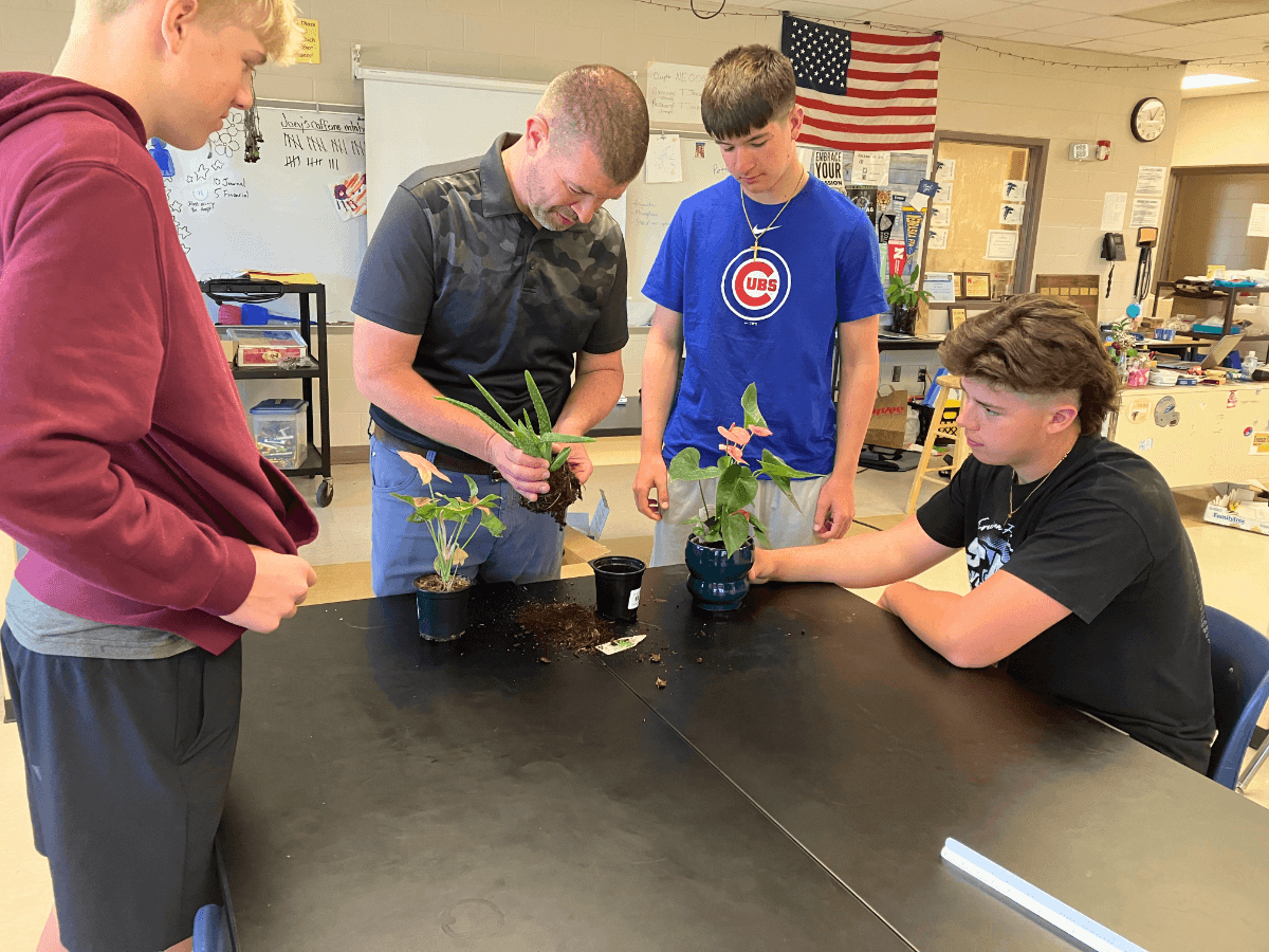 An FFA advisor works with students and plants in a classroom. 