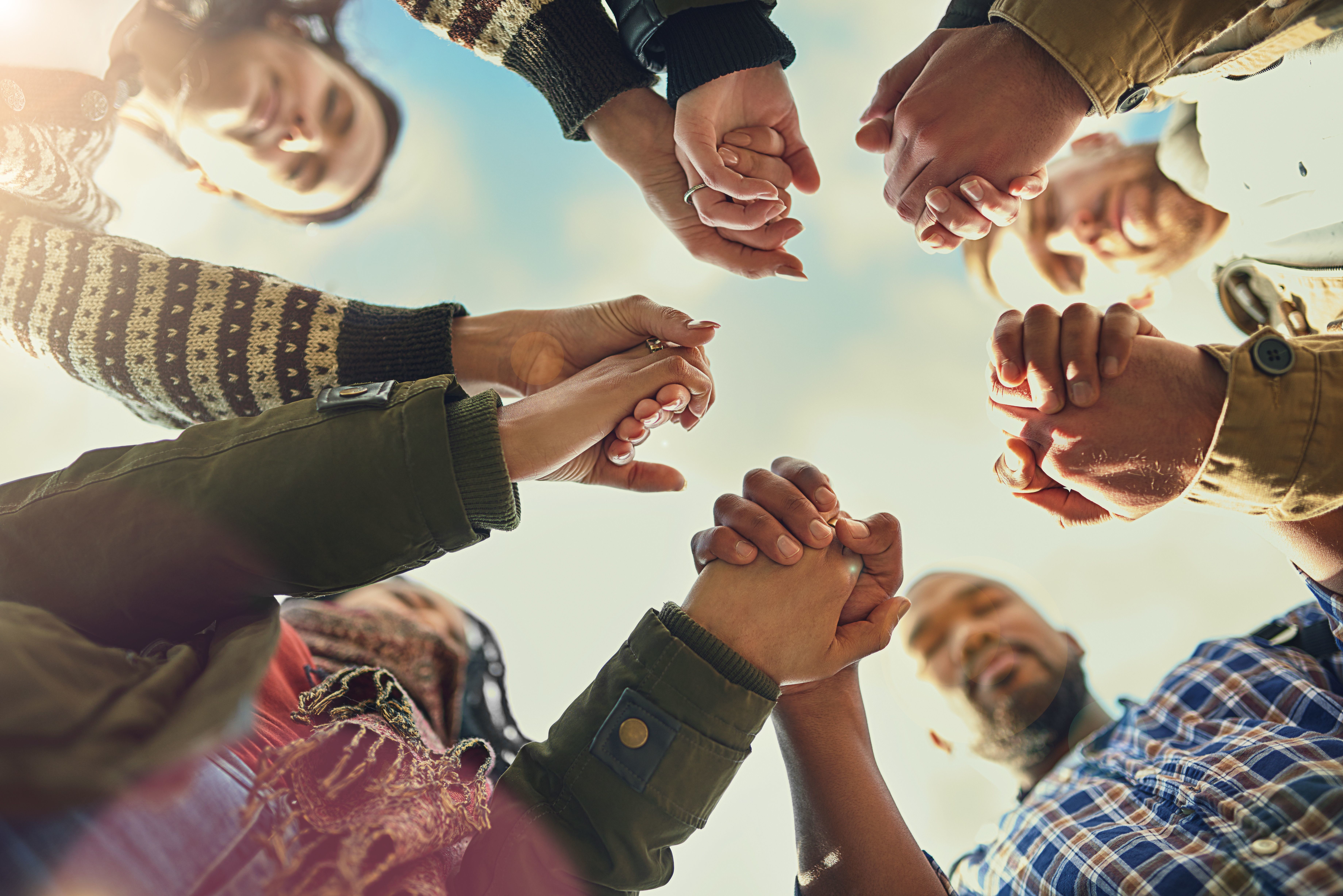 A group of people joining hands with their eyes closed. 