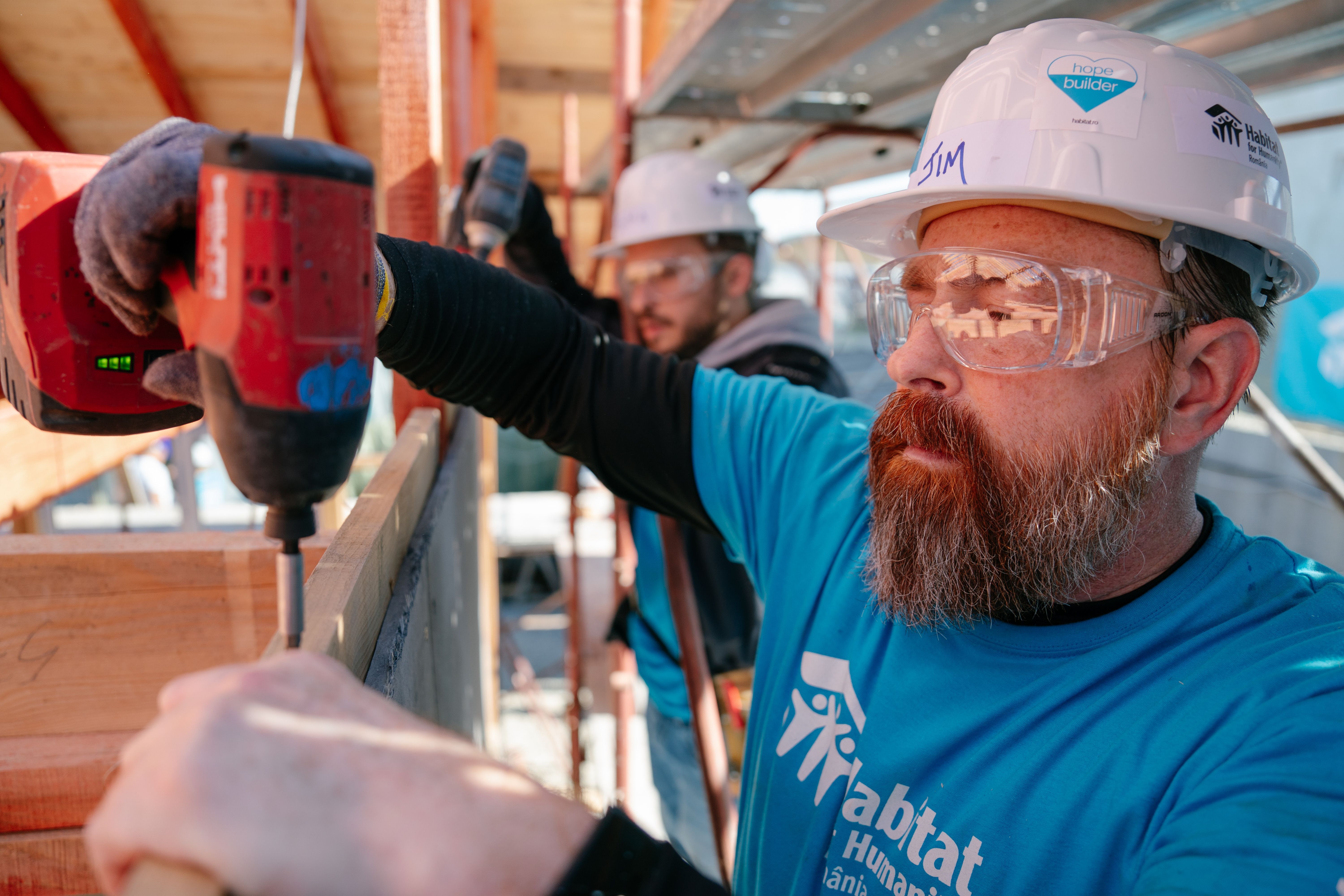 Construction volunteer drilling a nail to a frame