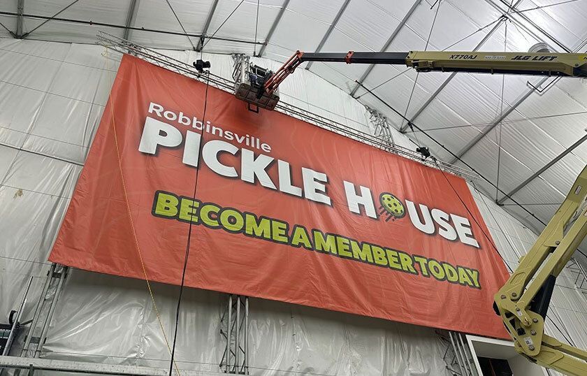Large red banner with text being installed inside a tall building.