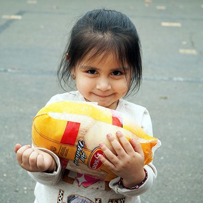 Young girl holding a fresh chicken at a distribution site