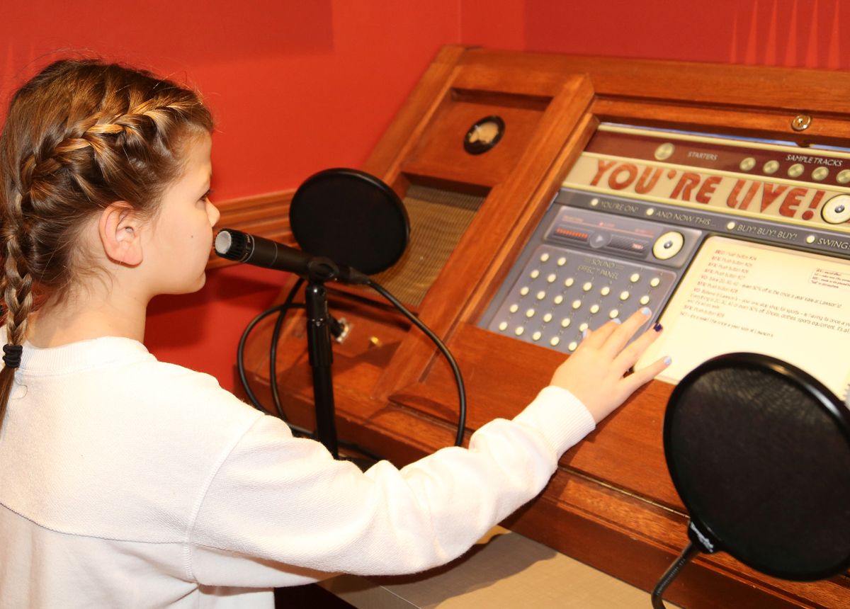 Girl playing with recording studio controls in the Smoky Hill Museum exhibit The Curiosity Shop.