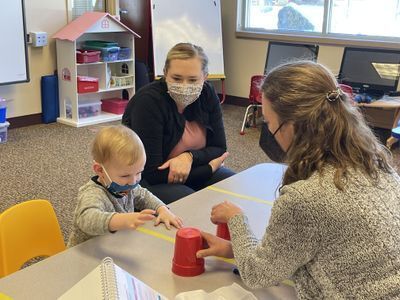 Teachers sitting around a baby.