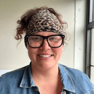 woman with leopard headband and thick black glasses wearing a blue shirt