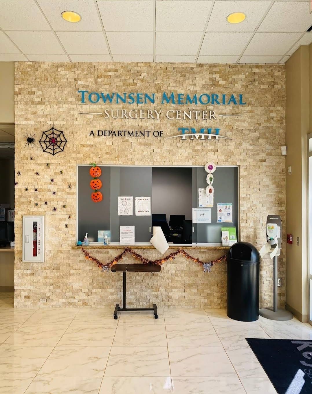 Interior lobby sign featuring raised dimensional acrylic lettering for “Townsen Memorial Surgery Center – A Department of TMH,” mounted on a textured stone wall with a festive Halloween display.