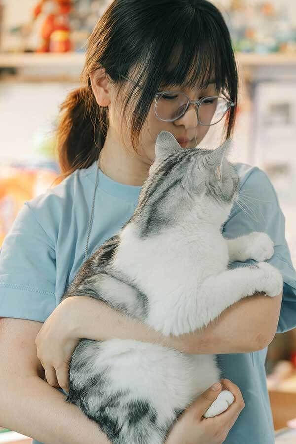 Woman holding a gray and white cat