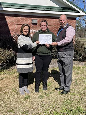 Dr. Cathy Gantz, left, and Wilmington Optimist Club President Ray Cockrell, right, present Thomas Academy student Celia Mitchell with her award for winning the essay competition.