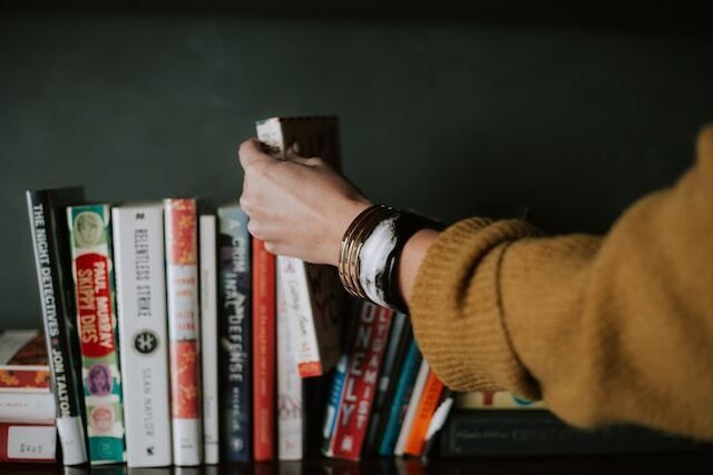 Hand picking out a book on a bookshelf