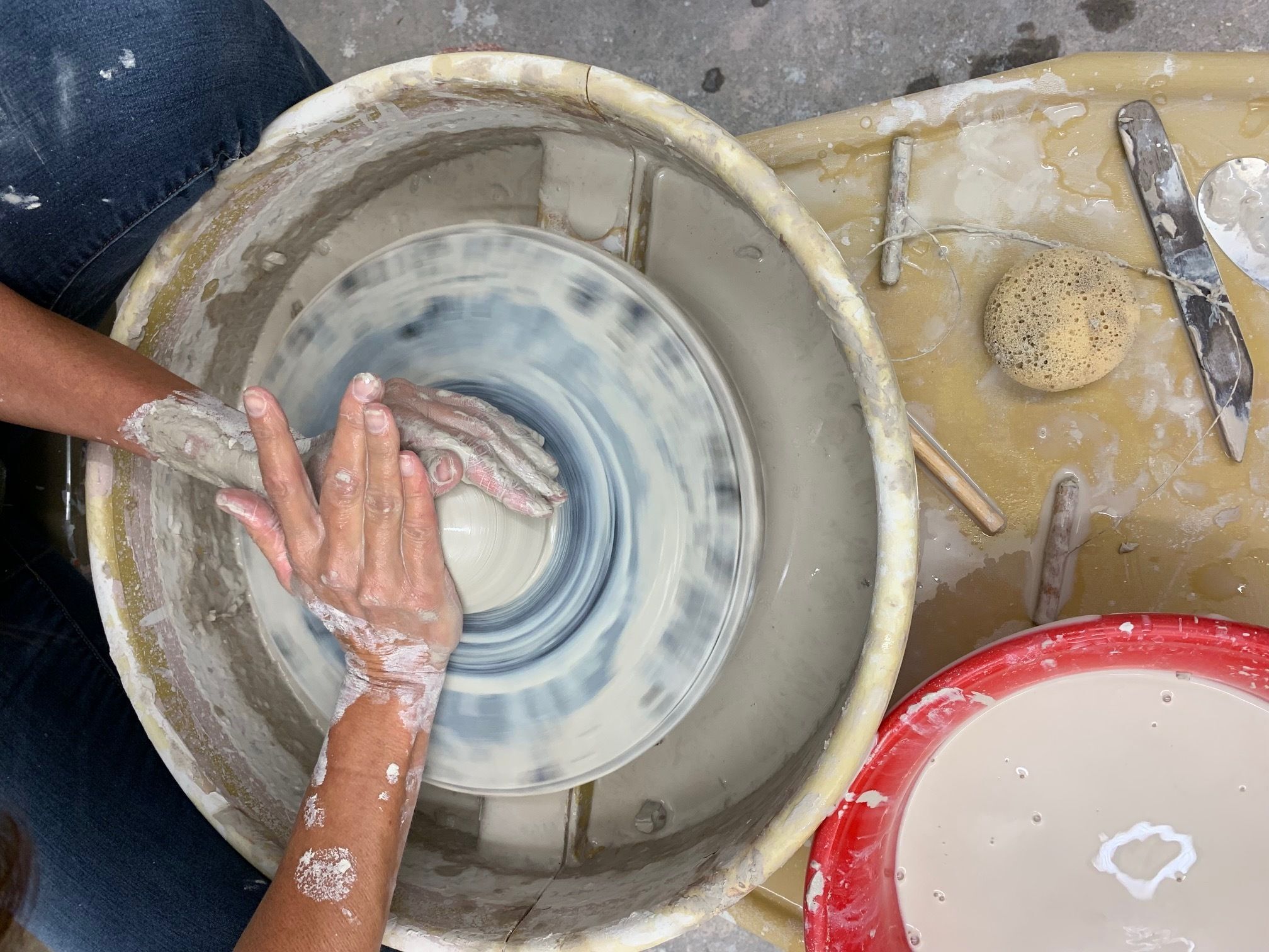 hands throwing pottery on a clay wheel