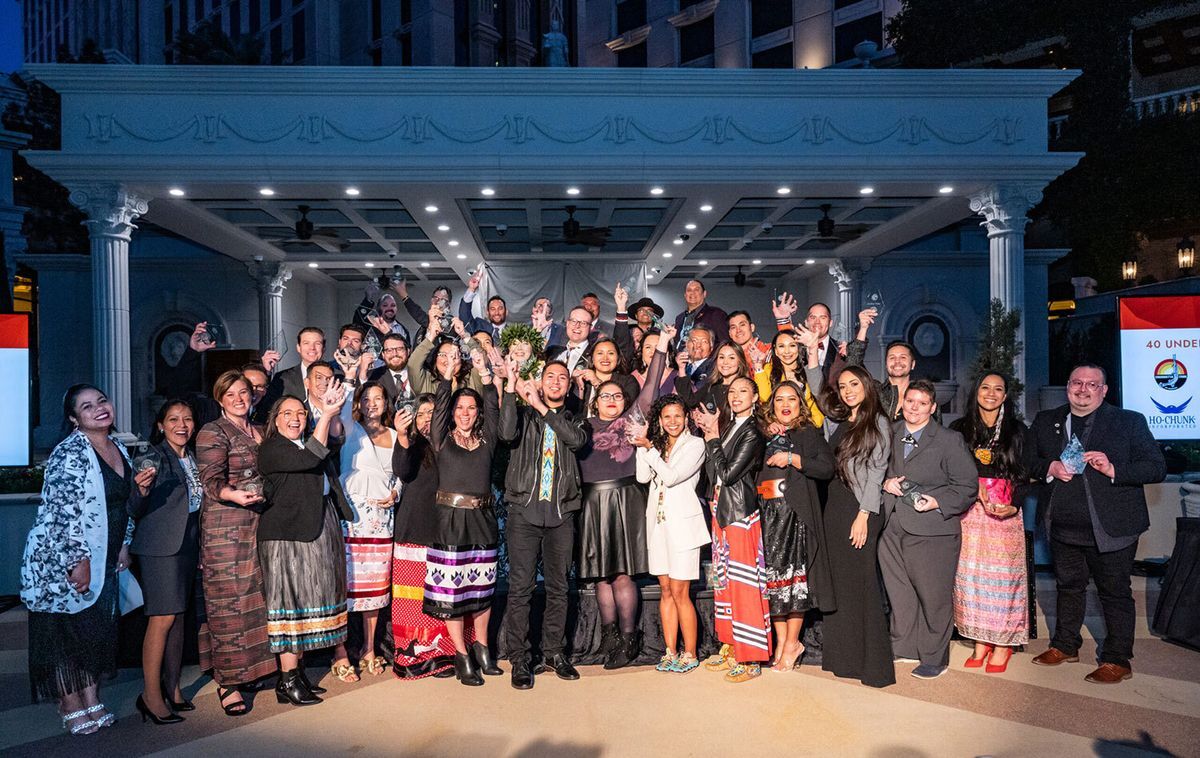 The 2023 40 Under 40 awards winners celebrating and holding small awards on stage.