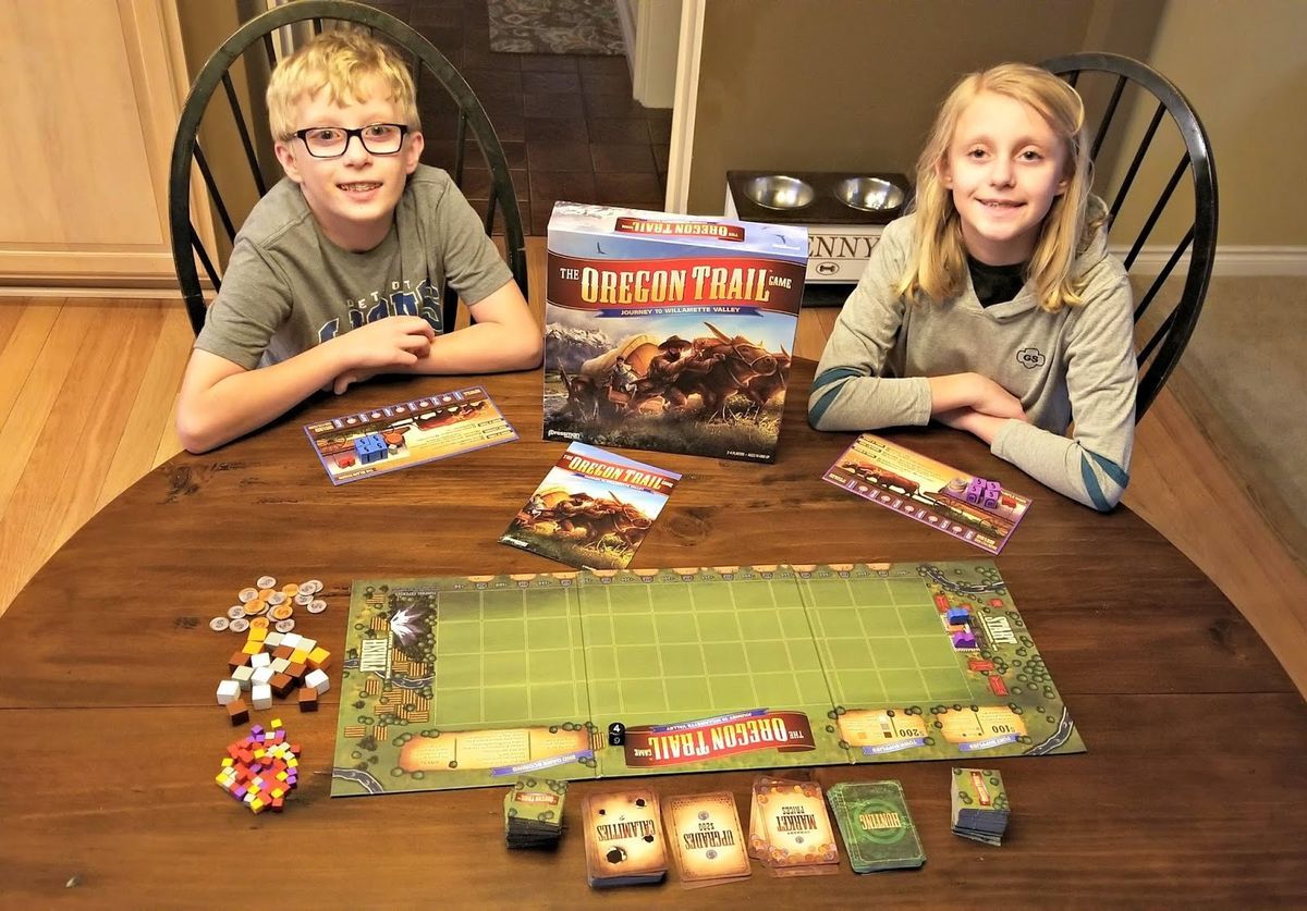 kids sitting at wood table playing board game