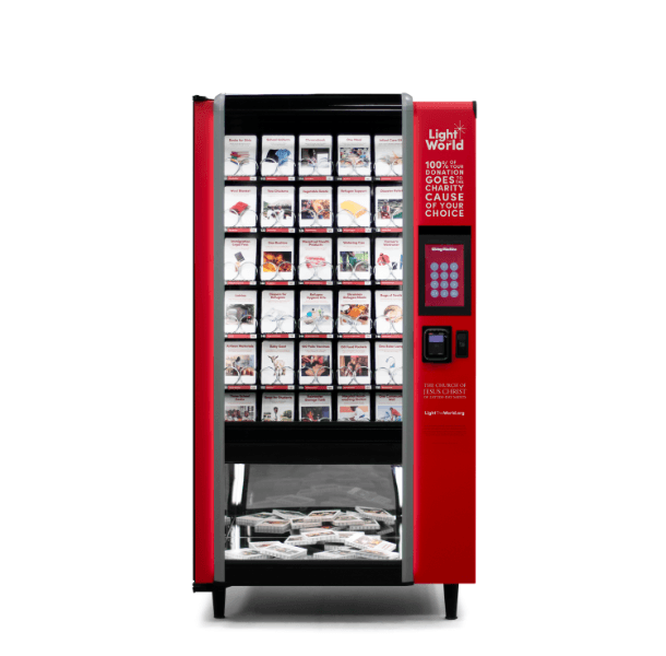 a red vending machine with the words light the world giving machine on it. Inside the giving machine is cards with items on them that people can choose to donate from.