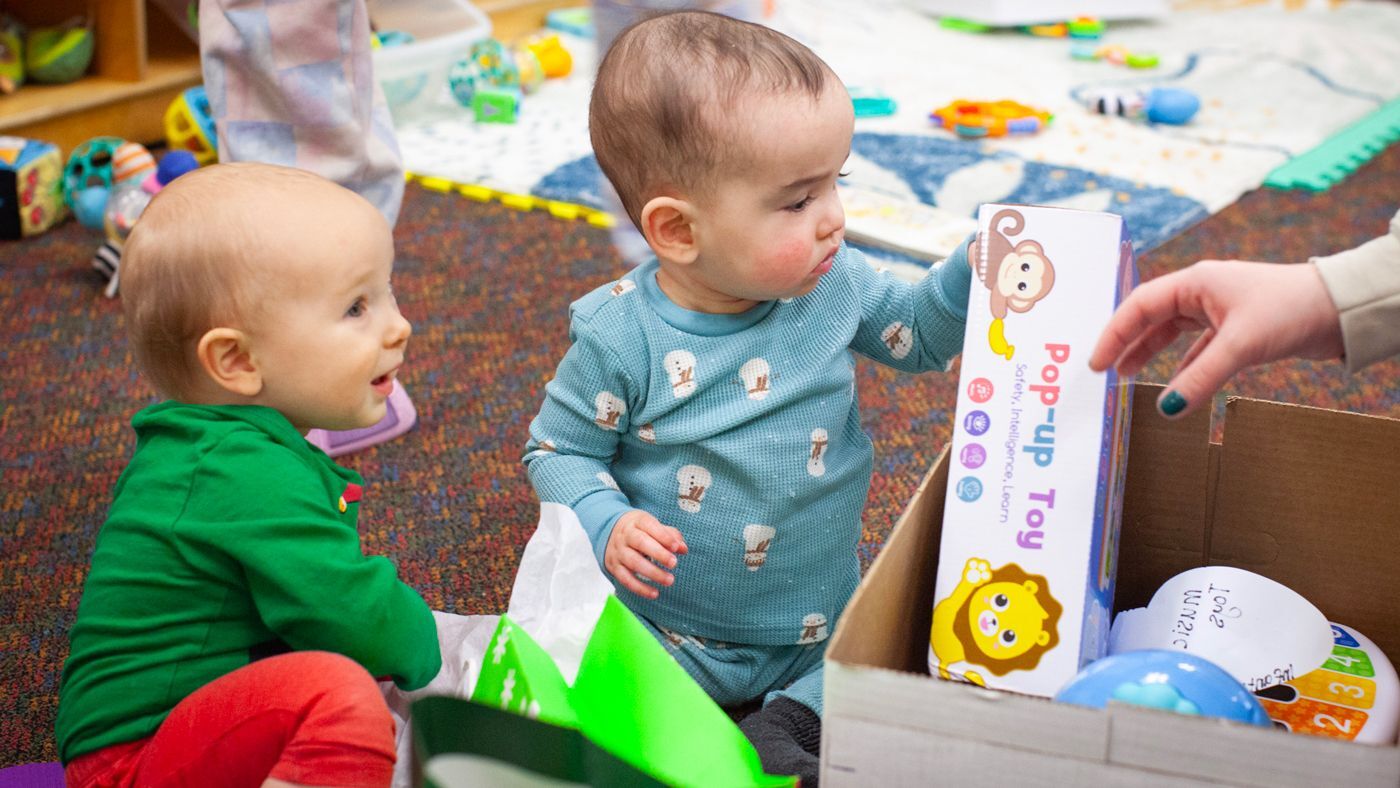 Two babies opening gifts from donors