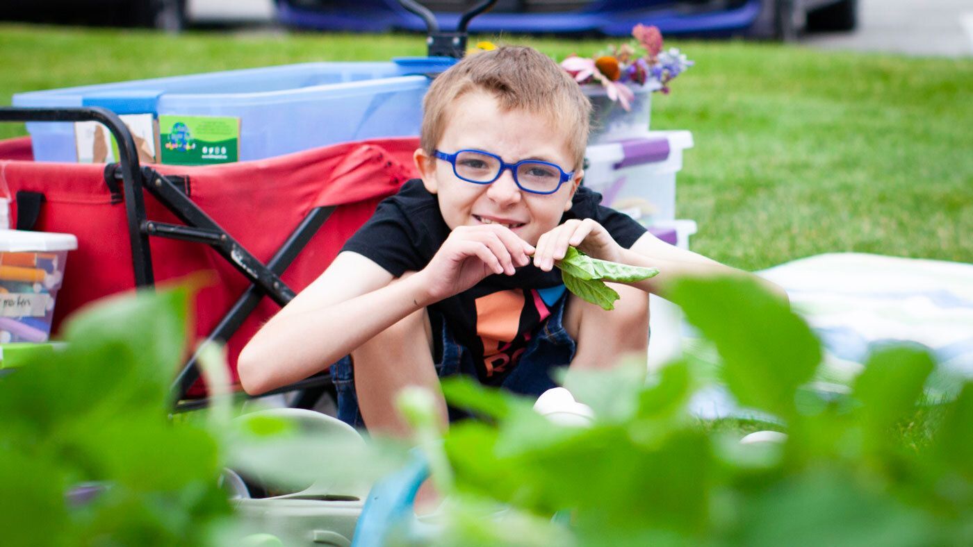 School-age child enjoying garden time during Summer Camp