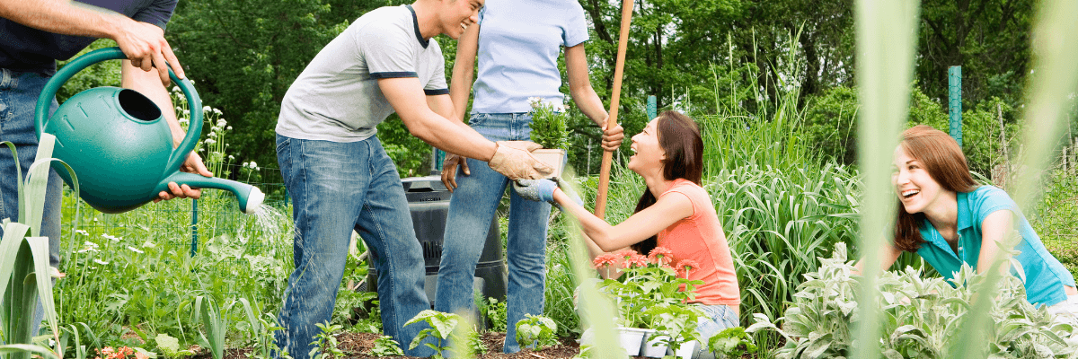 young people smiling and planting/tending to a garden 