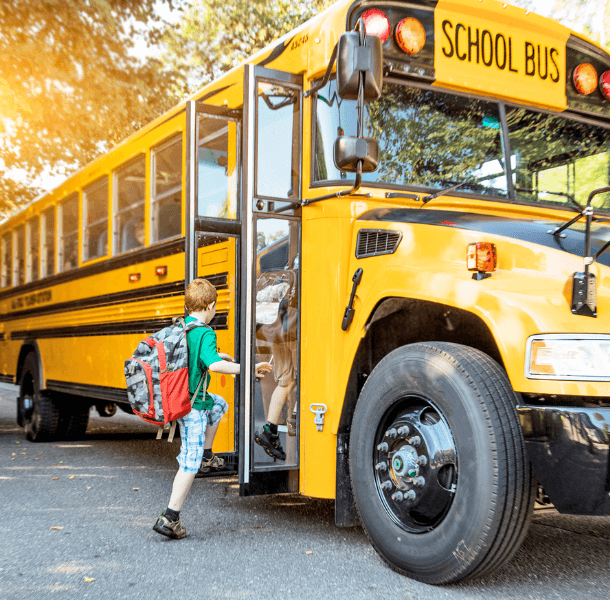 a boy with a backpack walking onto a school bus with 