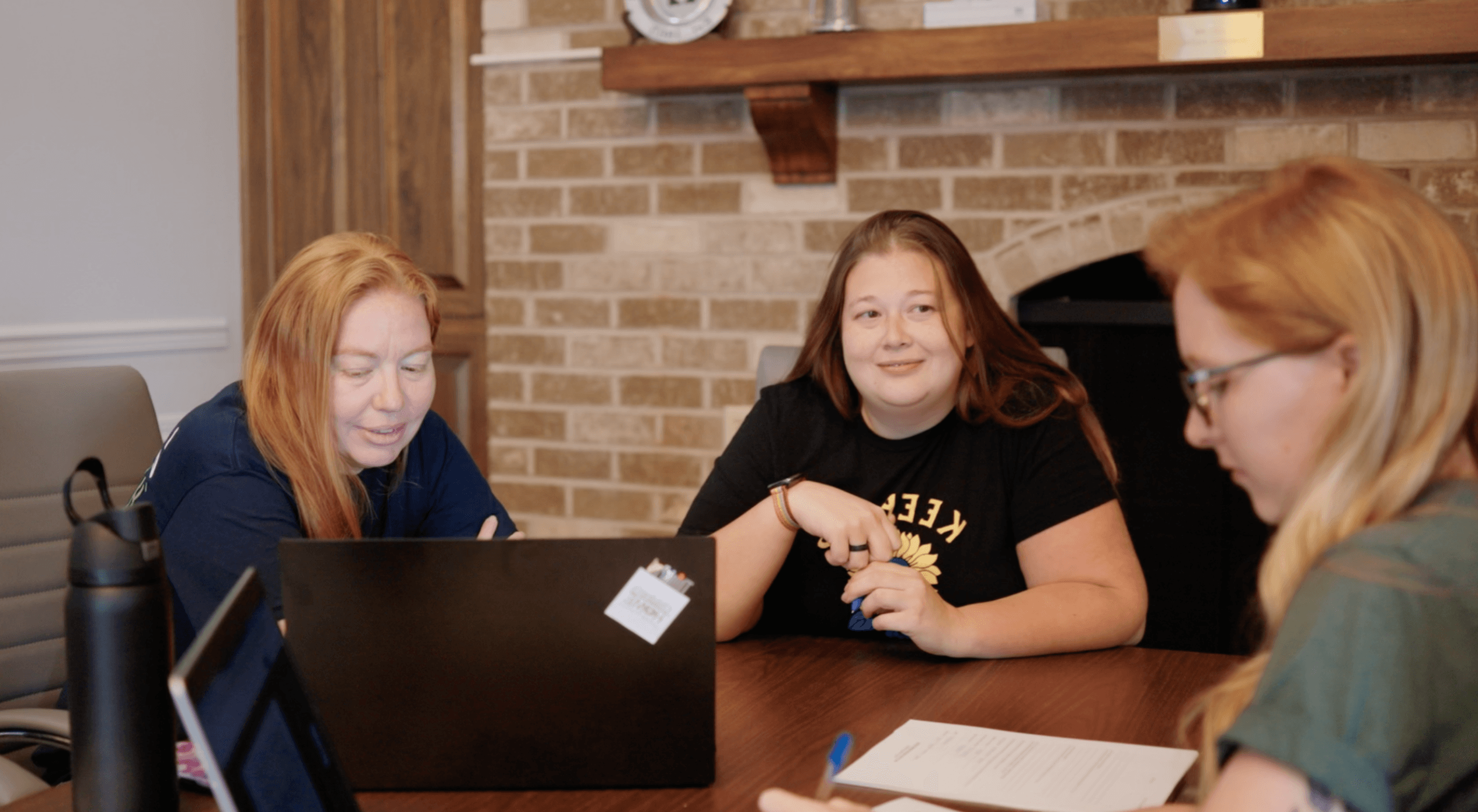 Three Children's Home of York team members sitting at a table doing work.