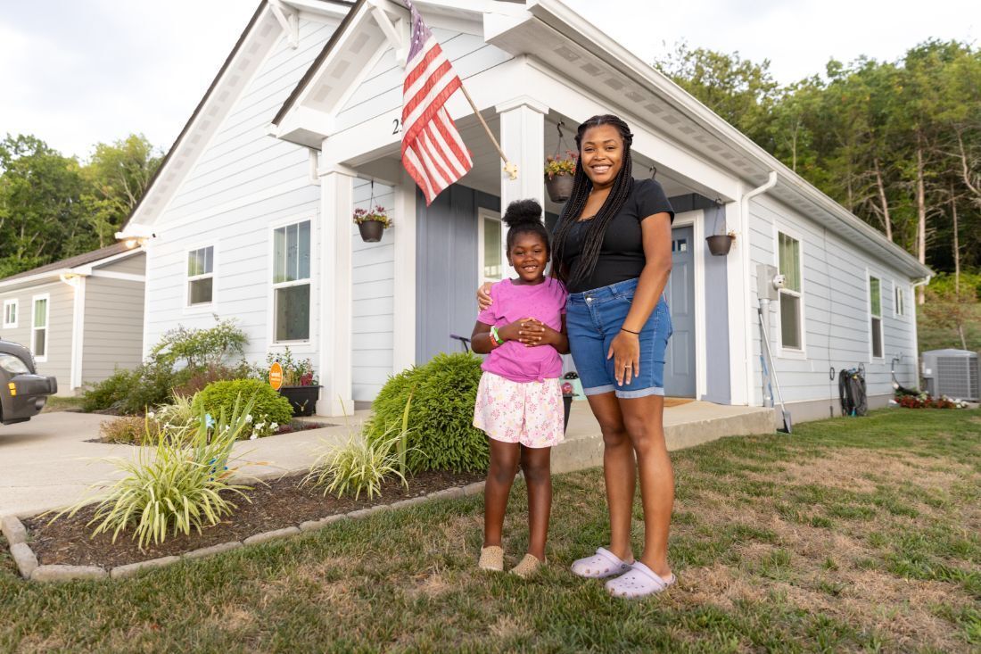 Mother and daughter smiling in front of a home.