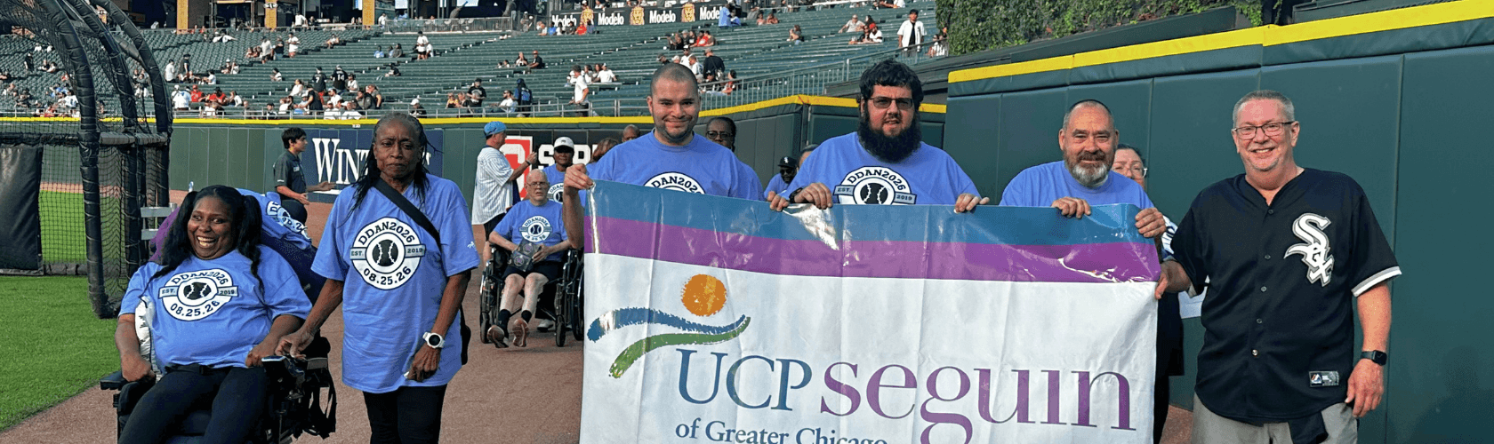 People walking on a baseball field holding a UCP Seguin banner