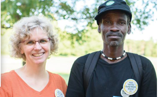 Female caseworker with male client, both smiling, outdoors in park