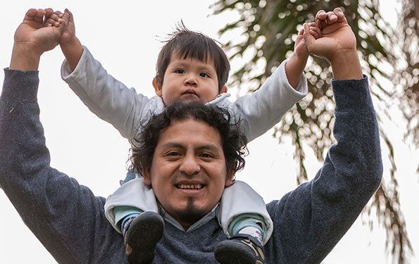 Smiling man holding baby on his shoulders