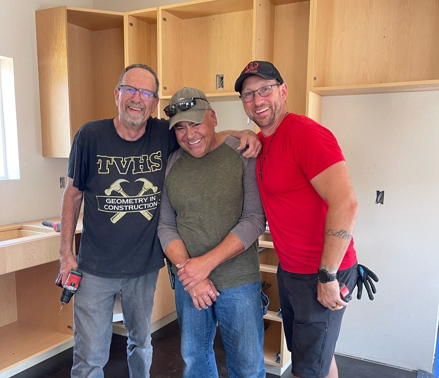 Abraham with a volunteer and staff working on a neighbor's house.