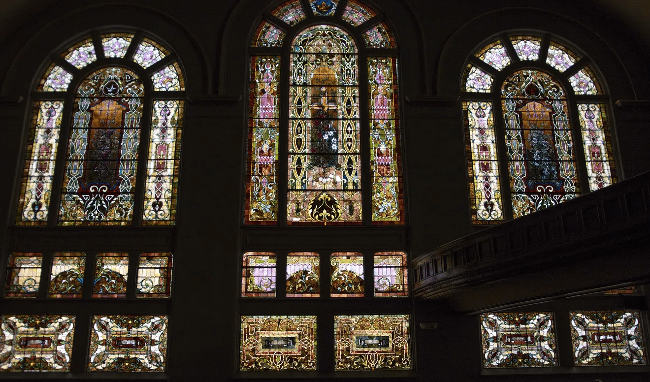 Stained glass windows inside Central Congregational Church in Galesburg, Illinois, featuring intricate designs of colored glass, floral and geometric patterns, and panels that glow with natural light from the 1897 sanctuary.