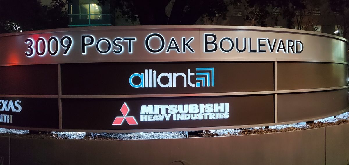 Night view of a large outdoor push-through acrylic monument sign at 3009 Post Oak Boulevard, featuring illuminated logos and text for Alliant and Mitsubishi Heavy Industries.